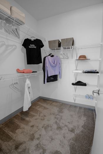 A white closet with a black shirt that says "Hello Saturday" hanging on the wall.